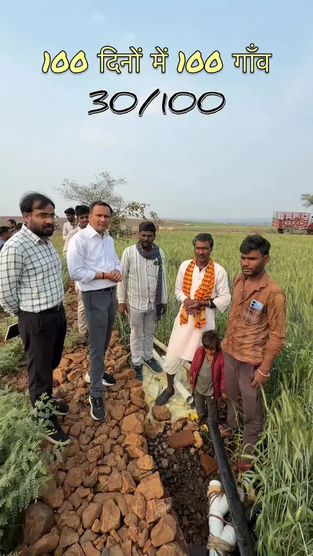 Village 35 of 100: project officers speaking with a group of farmers in a wheat field on a sunny morning